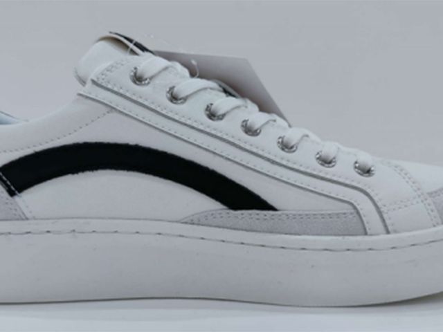 Side view of a finished white leather sample sneaker with a black stripe.