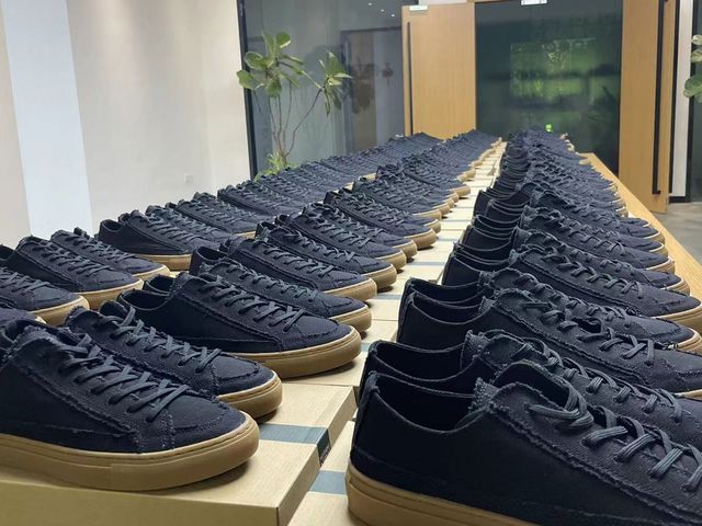 At one of our partner factories: rows of navy canvas sneakers with gum soles laid out on a table for inspection.