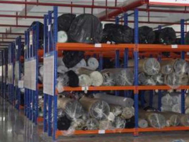 Warehouse racks holding rolls of fabric and material.