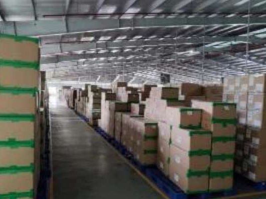 At one of our partner factories: a warehouse aisle stacked with boxed finished footwear.